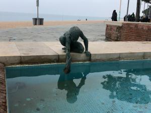 a statue of a man laying on the edge of a swimming pool at Excepcional 1ª línea de mar Platja d'Aro Elypalace 10-2 in Platja d'Aro