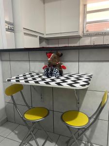 Un ours en peluche assis sur une table dans une cuisine dans l'établissement Apto Top Boqueirão Praia Grande., à Praia Grande