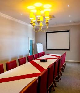 a conference room with a table and chairs and a screen at Hotel Dona Ana in Vilanculos