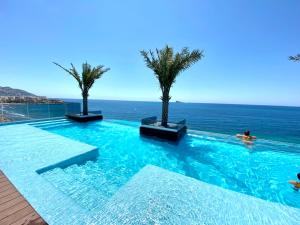 a swimming pool with palm trees and the ocean at Exclusive Apartments on the first line of Benidorm Mar y Sol in Benidorm