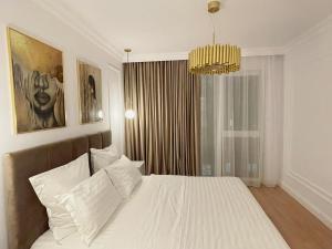 a bedroom with a white bed and a chandelier at Selling Sunset Apartments in Timişoara