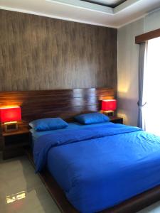 a bedroom with a large blue bed with two lamps at BUYAN LODGE lake view villa in Bedugul