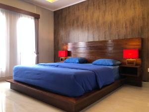 Schlafzimmer mit einem großen Bett mit einem Kopfteil aus Holz in der Unterkunft BUYAN LODGE lake view villa in Bedugul