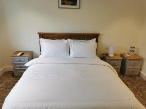 ein Schlafzimmer mit einem großen weißen Bett mit zwei Nachttischen in der Unterkunft Coliemore Acommodation Dalkey in Dalkey