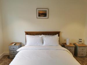 1 dormitorio con 1 cama blanca y 2 mesitas de noche en Coliemore Acommodation Dalkey, en Dalkey