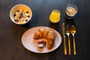a plate with a croissant and a bowl of cereal and a bowl at New Park Edition in Venlo