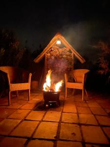 eine Feuerstelle mit zwei Stühlen und ein Haus in der Unterkunft myinsolite - Tiny-house, jacuzzi, brasero, piscine in Aigues-Mortes