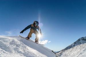 un hombre montando una tabla de snowboard por una pendiente cubierta de nieve en Crowne Plaza Queenstown, an IHG Hotel en Queenstown