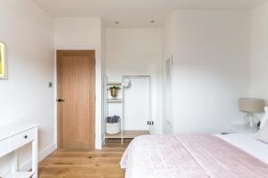 a white bedroom with a bed and a wooden door at The Penthouses, 9 Albion Mews in Chester