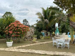 a garden with a table and chairs and flowers at Hospedagem Recanto das Orquideas in Quatis
