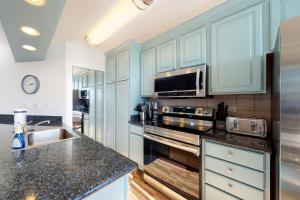 a kitchen with blue cabinets and a sink and a microwave at Maui Sunset A317 in Kihei