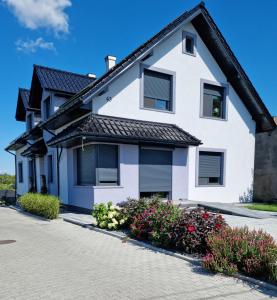 a white house with flowers in a driveway at Noclegi 24/h Leszczynek in Kutno