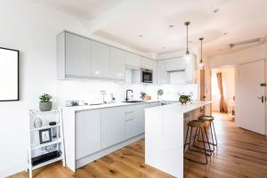 a white kitchen with white cabinets and a wooden floor at The Penthouses, 9 Albion Mews in Chester