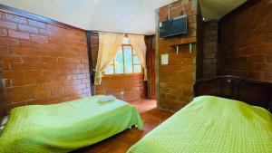 1 dormitorio con 2 camas en una pared de ladrillo en Hostería Kasadasa, en Santo Domingo de los Colorados