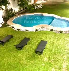 2 ligstoelen in het gras naast een zwembad bij Hermosa y Amplia Casa en Pie de la Cuesta in Coyuca