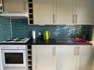 a kitchen with white cabinets and a black counter top at Driftwood WINTERTON VALLEY ESTATE Dog Friendly in Winterton-on-Sea