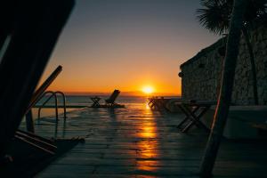 a sunset on the beach with chairs and the ocean at OurHabitas Tulum in Tulum
