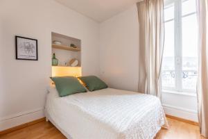 een witte slaapkamer met een bed en een raam bij Villa Alaisienne Confort in Chamalières