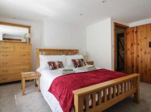 a bedroom with a large bed with a red blanket at Church Gate Cottage - Bridestowe in Bridestowe