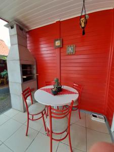 a table and chairs with a red wall at Chalet Sonho de Sophia in Urubici