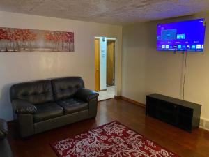 a living room with a leather couch and a flat screen tv at Nice 3 Bdr FREE Wine, Wi-fi and Parking in Milwaukee