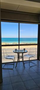 a table and two chairs with a view of the ocean at Acushla Accommodation Esplanade Living Self Check-In Self Check-Out in Adelaide