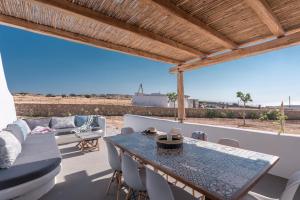 a patio with a table and chairs and a view of the ocean at Blue Harpist Villas in Koufonisia