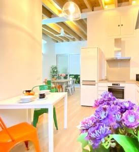 une cuisine et un salon avec une table et des fleurs violettes dans l'établissement Top-notch downtown house with private rooftop terrace and parking opt, à Séville