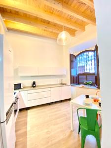 una cocina con armarios blancos y una mesa con una silla verde en Top-notch downtown house with private rooftop terrace and parking opt en Sevilla