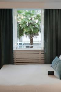 a bedroom with a bed and a palm tree outside a window at The Burrard in Vancouver
