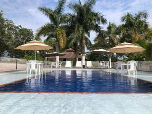 比亞維森西奧的住宿－Cabañas Campestres en Villavicencio，一个带椅子和遮阳伞的游泳池