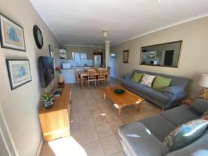 a living room with a couch and a table at Goose Valley Unit EE4 in Plettenberg Bay +6 photos
