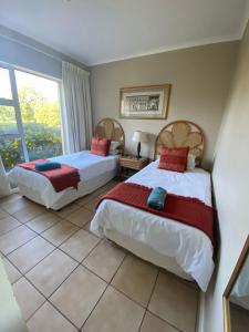 two beds in a room with a window at Goose Valley Unit EE4 in Plettenberg Bay