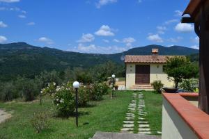 uma casa com um jardim com vista para as montanhas em Podere dei maddii em Roccastrada