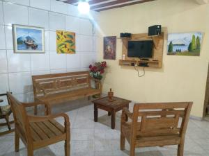 sala de estar con sillas de madera y TV en Sossego da Mamãe, en Paraty
