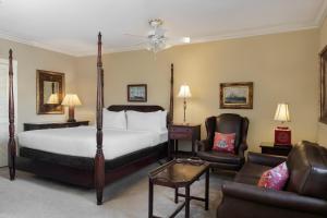 een slaapkamer met een bed en 2 stoelen en een bank bij Indigo Inn in Charleston