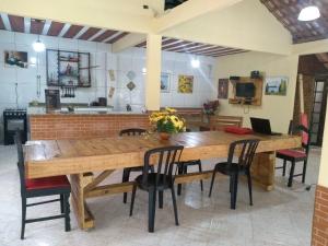 una gran mesa de madera con sillas y una cocina en Sossego da Mamãe, en Paraty