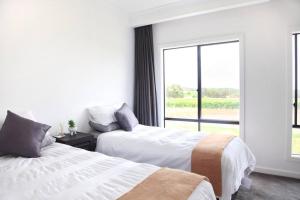 two beds in a white room with a window at The Red Door @ Barossa Valley Vineyard View in Nuriootpa
