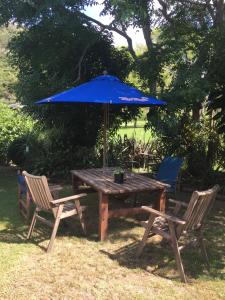 Studio at Matarangi في وايتيانغا: طاولة خشبية مع مظلة زرقاء وكرسيين