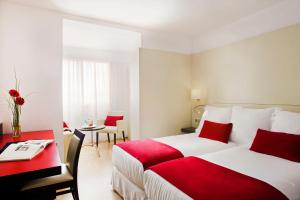 Pokój hotelowy z 2 łóżkami, stołem i biurkiem w obiekcie Grupotel Gravina w Barcelonie
