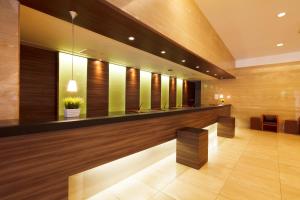 un vestíbulo de un hotel con suelos de madera y un bar en Kofu Kinenbi Hotel, en Kofu