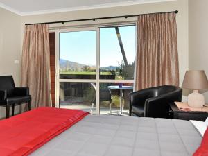 a bedroom with a bed and chairs and a large window at Mohua Motels in Takaka