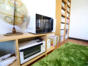 a room with a microwave and a television on a shelf at Haruno Guesthouse in Tosa