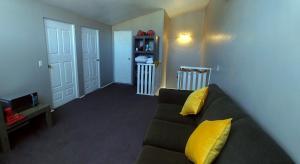uma sala de estar com um sofá preto com almofadas amarelas em Departamentos - Cabañas Sias em Creel