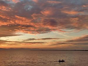 zwei Personen in einem Boot auf dem Wasser bei Sonnenuntergang in der Unterkunft Olana Bed and Breakfast in Labrador