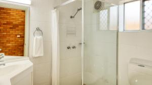 a white bathroom with a shower and a sink at Court Street Motel in Parkes +6 photos