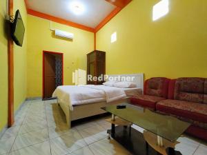 a hotel room with a bed and a couch at Hotel Hing Amimah near Bau Bau Port RedPartner in Baubau