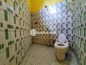 a bathroom with a toilet in a tiled wall at Hotel Hing Amimah Mitra RedDoorz in Baubau