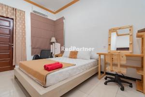 a bedroom with a bed and a desk and a mirror at Langkar Guest House Syariah Mitra RedDoorz in Samarinda