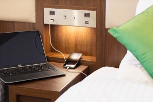 a laptop computer on a wooden table next to a bed at Hotel Mystays Kagoshima Tenmonkan in Kagoshima